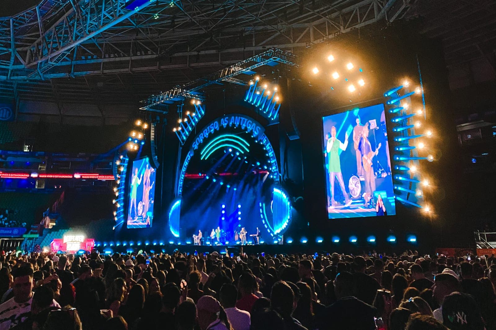 Palco com telões e estrutura de luz visto da pista lotada